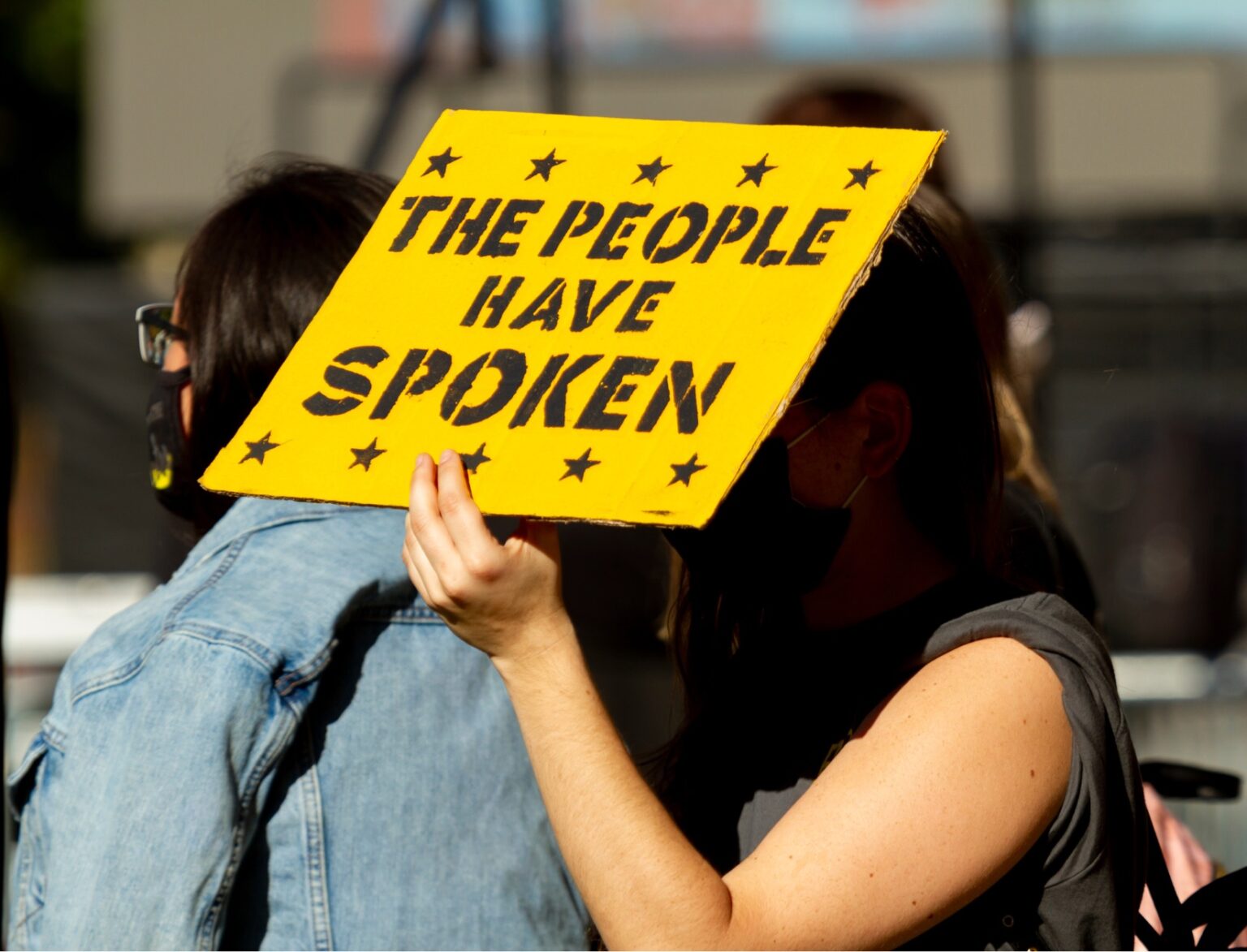 Person holding yellow sign that says The People Have Spoken