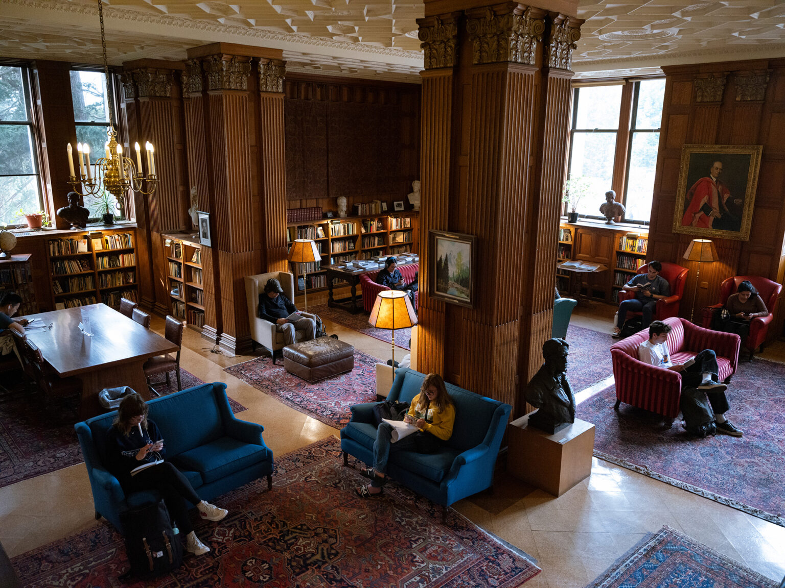 People sit on couches with books in a library reading room